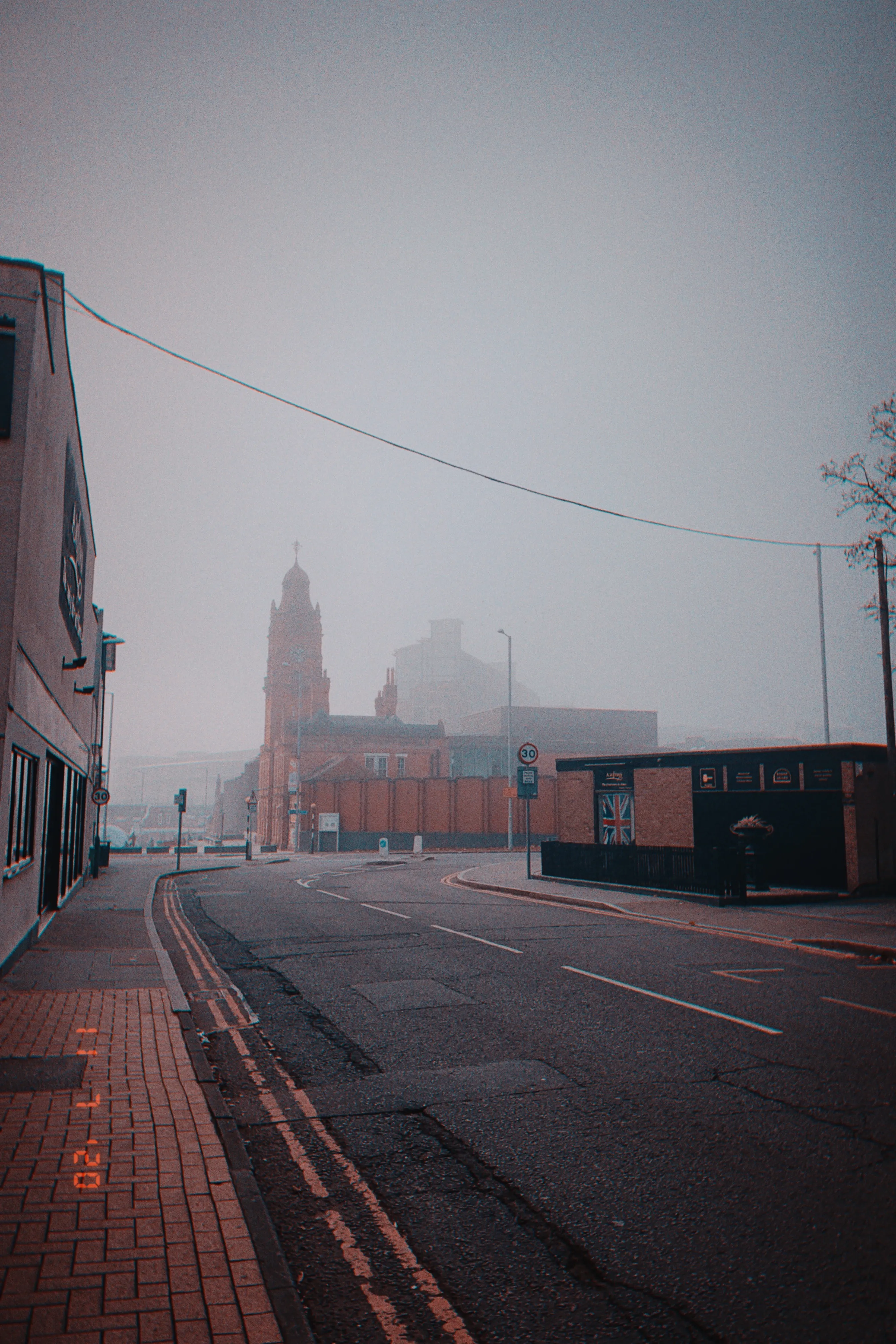 A foggy street, with a square and a brick building in the distance