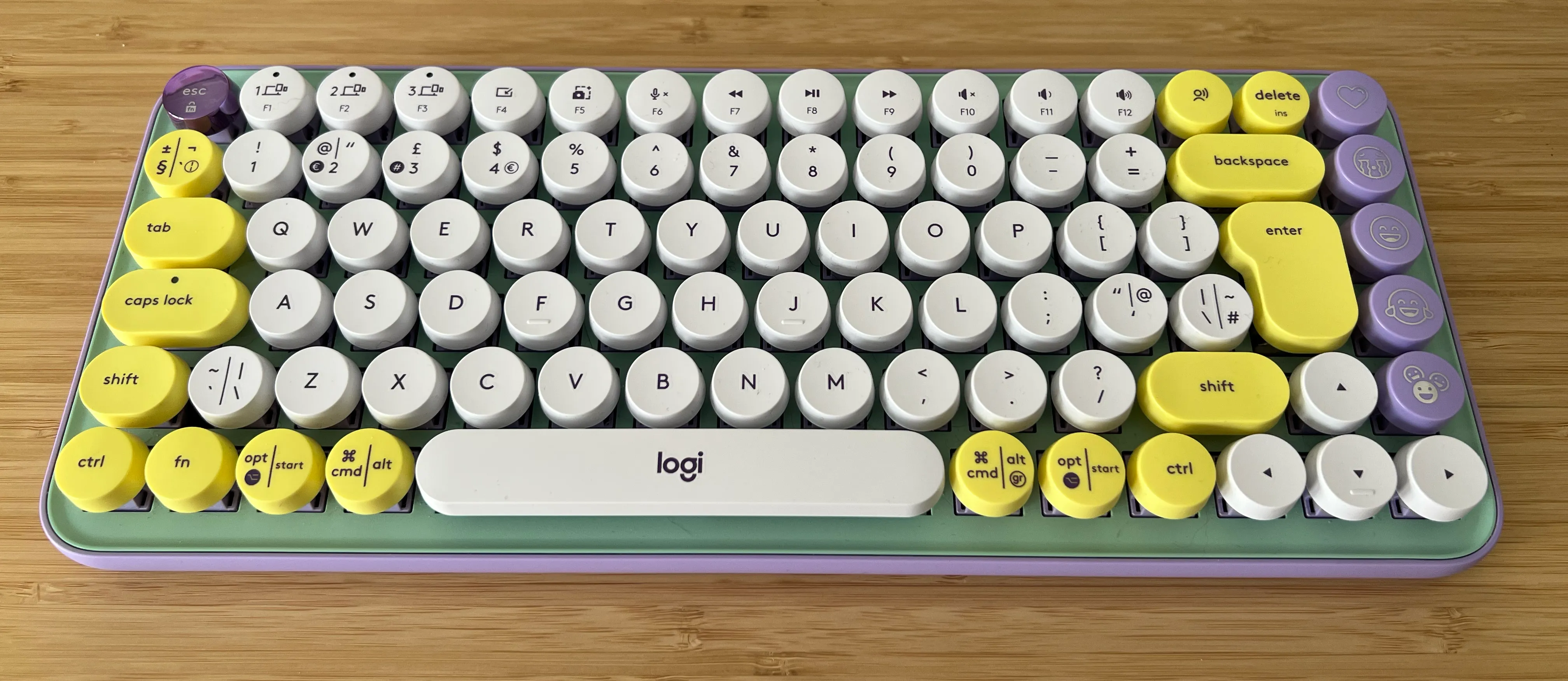 A 60% wireless keyboard with round keycaps. The board is mint green and lilac, and the keys are white and yellow.