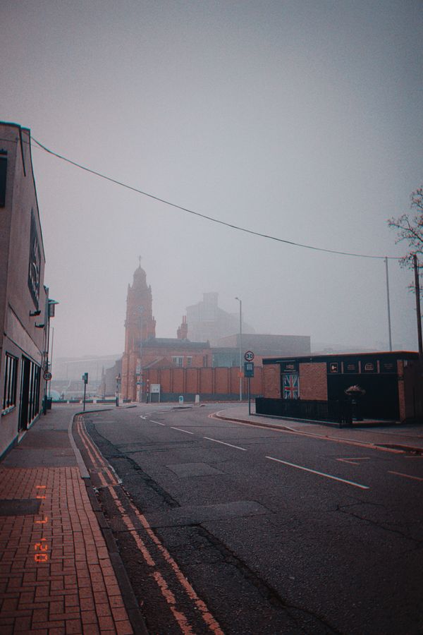A foggy street, with a square and a brick building in the distance