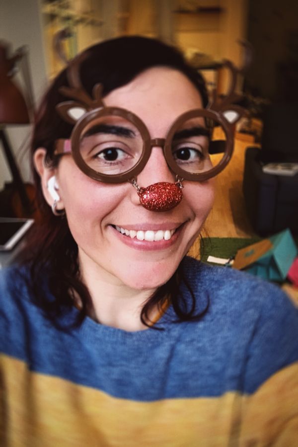 A selfie of me wearing a pair of reindeer glasses: those are brown with antlers coming off the eyes and a red nose linked to them by a short chain.